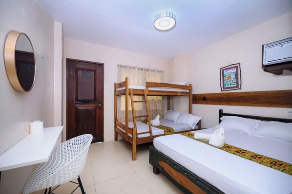A room with a bunk bed, a desk, a chair, a door, a window with curtains, and a wall-mounted air conditioner.