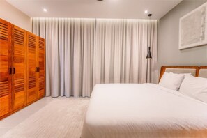 A bedroom with a large bed, wooden wardrobe, and a curtain. - Beachfront 2BR Condo w/ Balcony • Sol de Arena E4 (Las Terrenas)