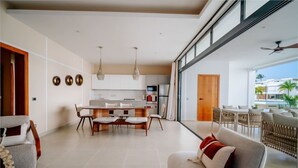 A modern living room with a sofa, dining area, and kitchen. - Beachfront 2BR Condo w/ Balcony • Sol de Arena E4 (Las Terrenas)