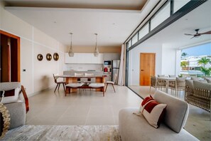 A modern living room with a sofa, dining area, and kitchen. - Beachfront 2BR Condo w/ Balcony • Sol de Arena E4 (Las Terrenas)