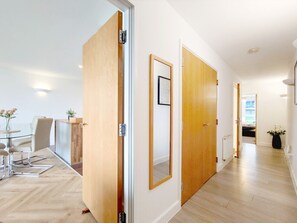 Ein modernes Interieur mit Essbereich, Holztüren und einem Gang zu einem weiteren Zimmer.