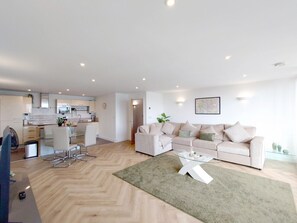 Ein modernes Wohnzimmer mit einer Couch, einem Couchtisch und einem Essbereich mit Stühlen.