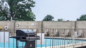 A barbecue grill near a swimming pool with lounge chairs and a brick wall in the background. - The River Condos - Detroit, Michigan (Detroit)