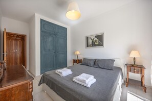 A bedroom with a bed, two bedside tables, a wardrobe, and a hanging light fixture. - Apartment 'Central  - Lagos' with Sea View, Balcony and Wi-Fi (Lagos)