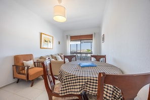 A dining area with a checkered tablecloth, wooden chairs, a sofa, and a framed picture on the wall. - Apartment 'Central  - Lagos' with Sea View, Balcony and Wi-Fi (Lagos)