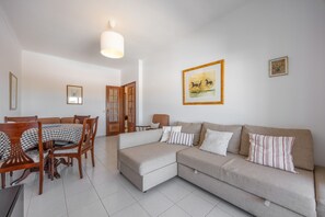 A living room with a sofa, a dining table with chairs, and a painting on the wall. - Apartment 'Central  - Lagos' with Sea View, Balcony and Wi-Fi (Lagos)