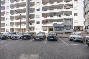 Ein mehrstöckiges Wohngebäude mit Parkplatz davor.