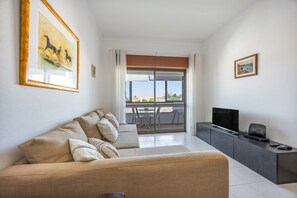 A living room with a sofa, a TV, a small table, and a balcony with a view. - Apartment 'Central  - Lagos' with Sea View, Balcony and Wi-Fi (Lagos)