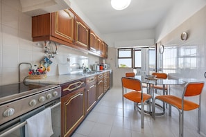 A kitchen with wooden cabinets, a stove, and a dining area with orange chairs. - Apartment 'Central  - Lagos' with Sea View, Balcony and Wi-Fi (Lagos)