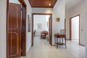 A hallway with wooden doors, a tiled floor, a seating area with a sofa and chairs, and a small table with a sign. - Apartment 'Central  - Lagos' with Sea View, Balcony and Wi-Fi (Lagos)