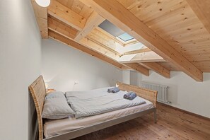 A bedroom with a sloped ceiling, a skylight, a bed with pillows, and a radiator. - Bed and Breakfast 'Formigher' with Mountain View and Wi-Fi (Limana)
