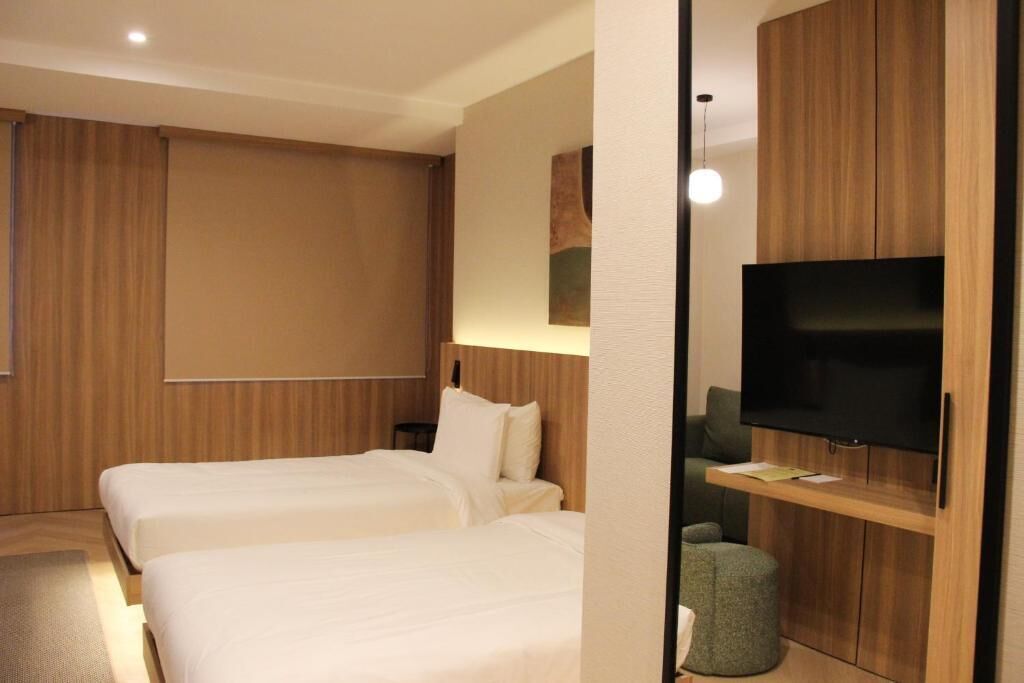 A hotel room with two beds, a TV, and a wooden cabinet.