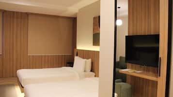A hotel room with two beds, a TV, and a wooden cabinet.