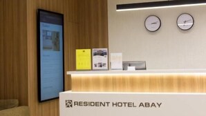 A reception desk with a clock, a digital display, and a sign for the Resident Hotel Abay. - Resident Hotel Abay (Almaty)