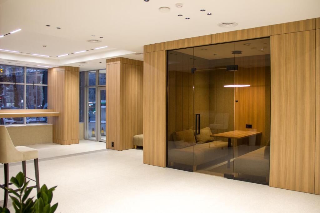 A modern interior with a glass partition, wooden paneling, and a seating area with a bench and a table.