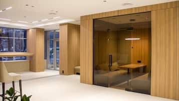 A modern interior with a glass partition, wooden paneling, and a seating area with a bench and a table.