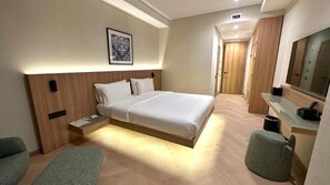 Una habitación de hotel moderna con cama, mesita de noche, silla y espejo.
