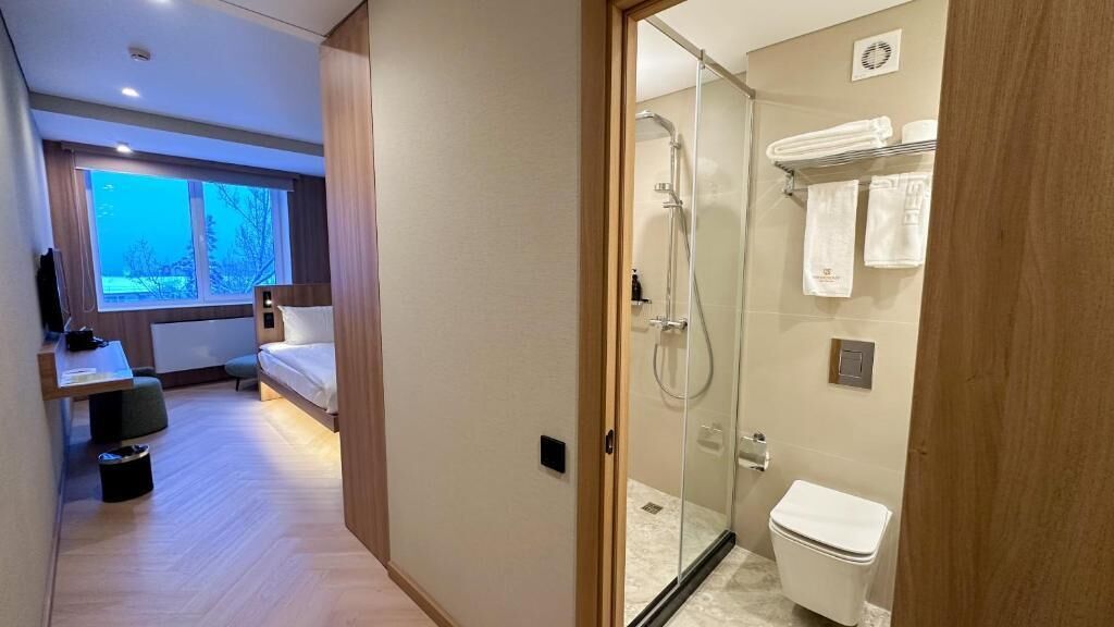 Un baño moderno con cabina de ducha de vidrio, inodoro y perchero para toallas.