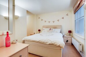 A bedroom with a bed, bedside tables, a dresser, a window, and a wall-mounted lamp. - Charming 2BDR London Apt in Kings Cross Sleeps 5 (Greater London)