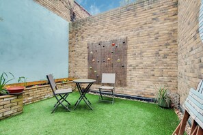 A patio with a brick wall, a wooden fence, and a small table and chairs. - Charming 2BDR London Apt in Kings Cross Sleeps 5 (Greater London)