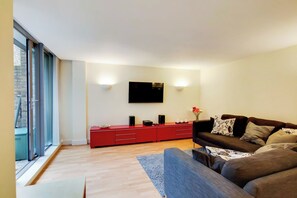 A modern living room with a red entertainment unit, a black sofa, and a large window. - Charming 2BDR London Apt in Kings Cross Sleeps 5 (Greater London)