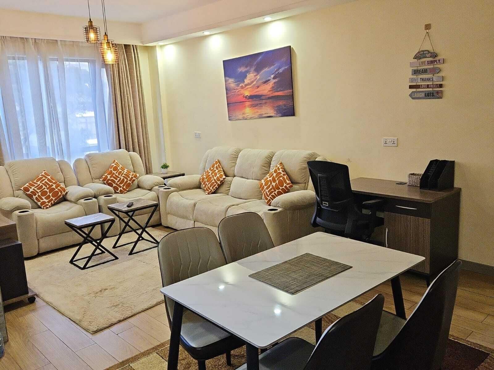 Un salon moderne avec un ensemble de canapés, une table à manger et un tableau accroché au mur.