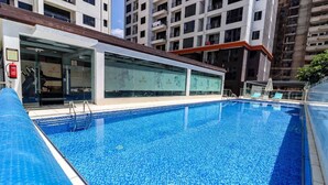 Ein Schwimmbecken mit klarem, blauem Wasser, umgeben von einem modernen Gebäude mit Glasfenstern und einem Flachdach.