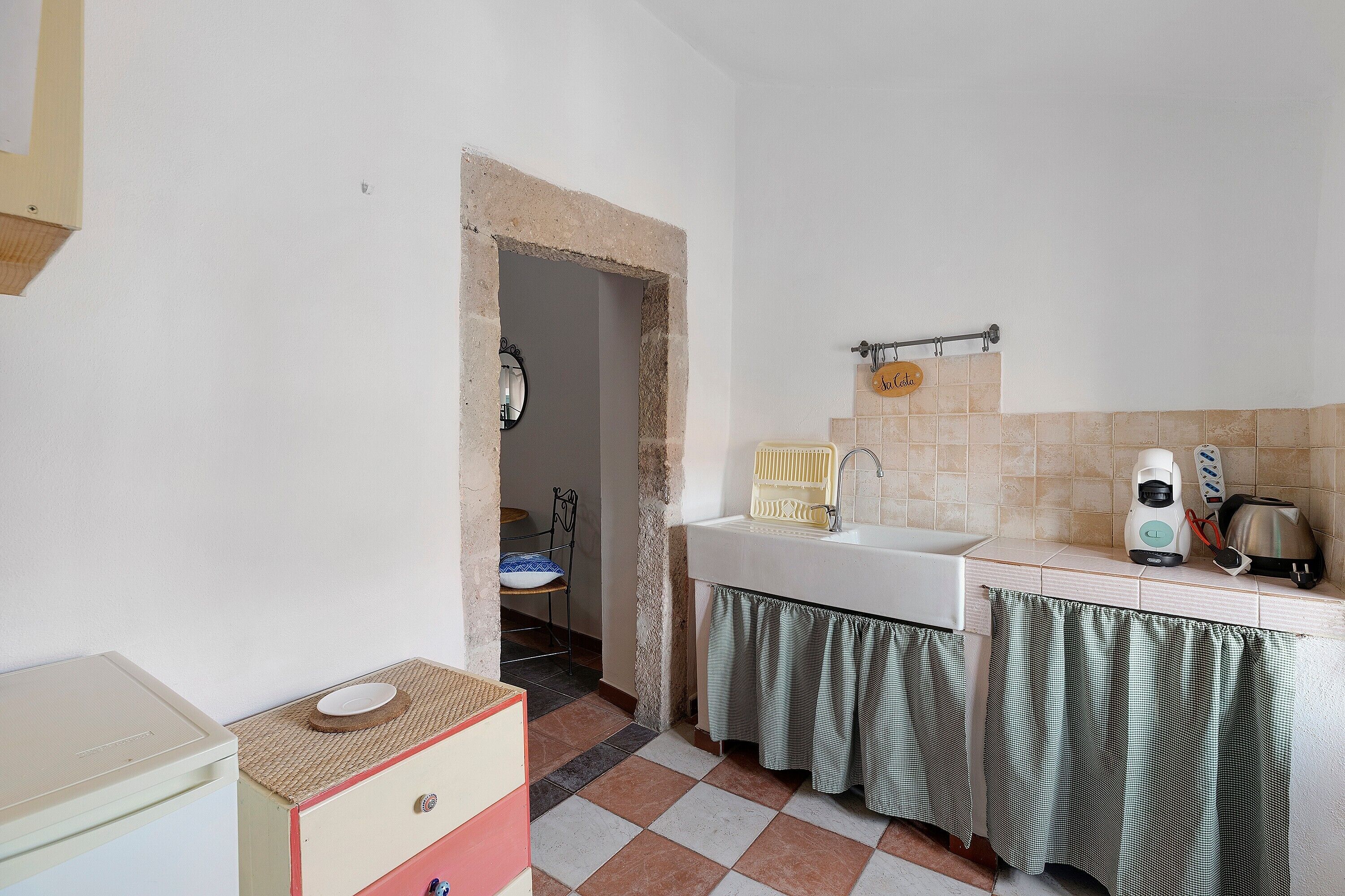 A compact kitchen with a sink, a coffee maker, and a kettle.