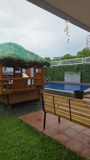 A wooden structure with a thatched roof, a pool, and a bench. - Staycation in San Rafael Bulacan (San Rafael)
