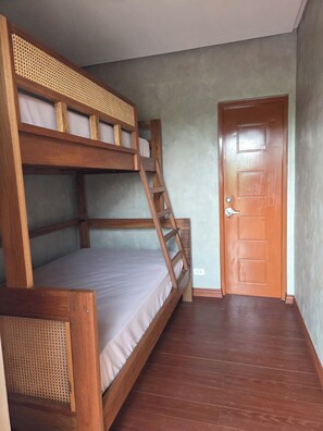 A bunk bed with a wooden ladder, a wooden door, and a plain wall.