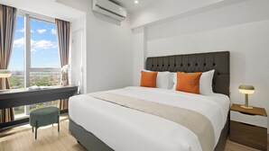 Et moderne hotelværelse med en stor seng, et skrivebord og udsigt over byen.
