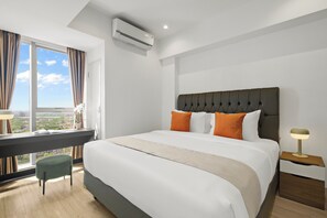 Ein modernes Hotelzimmer mit einem großen Bett, einem Schreibtisch und Blick auf die Stadt.