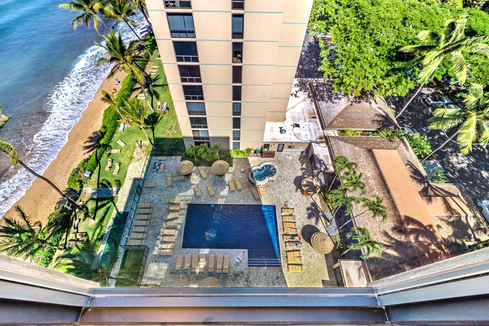 A hotel with a rooftop pool, lounge chairs, and a view of the beach.