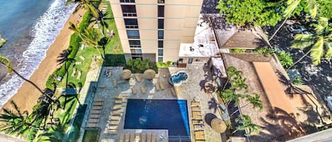 A hotel with a rooftop pool, lounge chairs, and a view of the beach.
