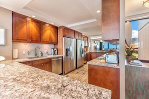 A modern kitchen with granite countertops, stainless steel appliances, and wooden cabinets. - Mahana Resort |  2 Oceanfront Villas, Sleeps 8 | Car Incl. w/ 6+Nights | ML-4190 by KBM (Lahaina)