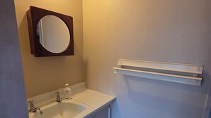 Un baño con lavamanos blanco, un espejo y un toallero.