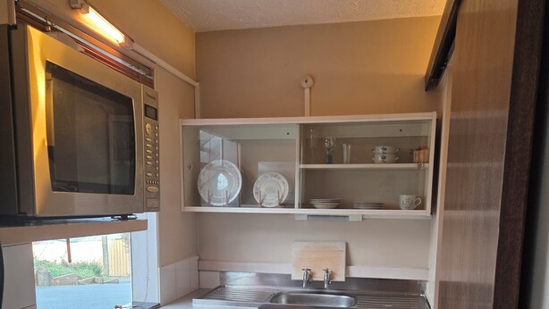 Una cocina compacta con microondas, estufa, lavaplatos y armarios.