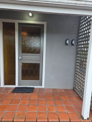 A house entrance with a double door, a small window, and a metal gate. - Bellbird Hideaway - Fireside Studio in Hanmer Village (Hanmer Springs)
