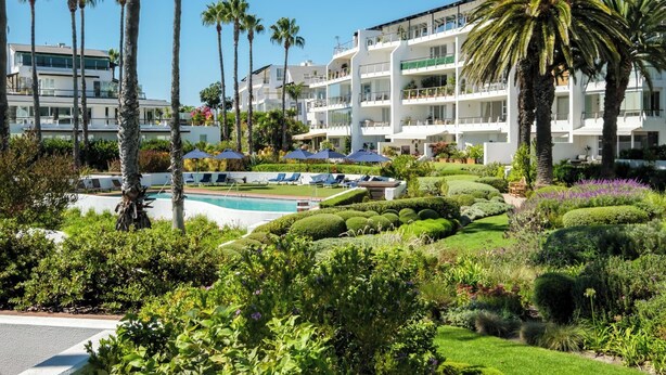 Ein Resort mit Swimmingpool, Palmen und gepflegten Gärten.