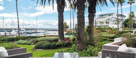 A patio with wicker furniture, a glass-top table, and a view of a marina with boats.