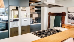 Eine moderne Küche mit eingebautem Gasherd, einem Kühlschrank und Holzschränken.