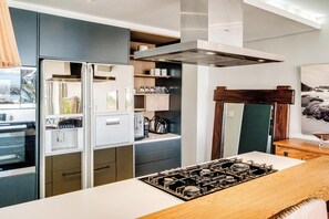 Eine moderne Küche mit eingebautem Gasherd, einem Kühlschrank und Holzschränken.