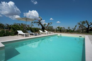 A swimming pool with lounge chairs and an umbrella. - Beyond the Cones (Puglia)