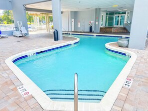Una piscina amb vora enrajolada, un senyal que prohibeix saltar i un posto de socorrisme.