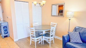 A dining area with a round table and four chairs, a chandelier, a mirror, a sofa, and a lamp. - Harbourgate Resort and Marina 504 (North Myrtle Beach)