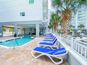 A pool area with lounge chairs and a building with balconies. - Harbourgate Resort and Marina 504 (North Myrtle Beach)