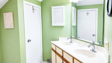 A bathroom with two sinks, a large mirror, and a door.