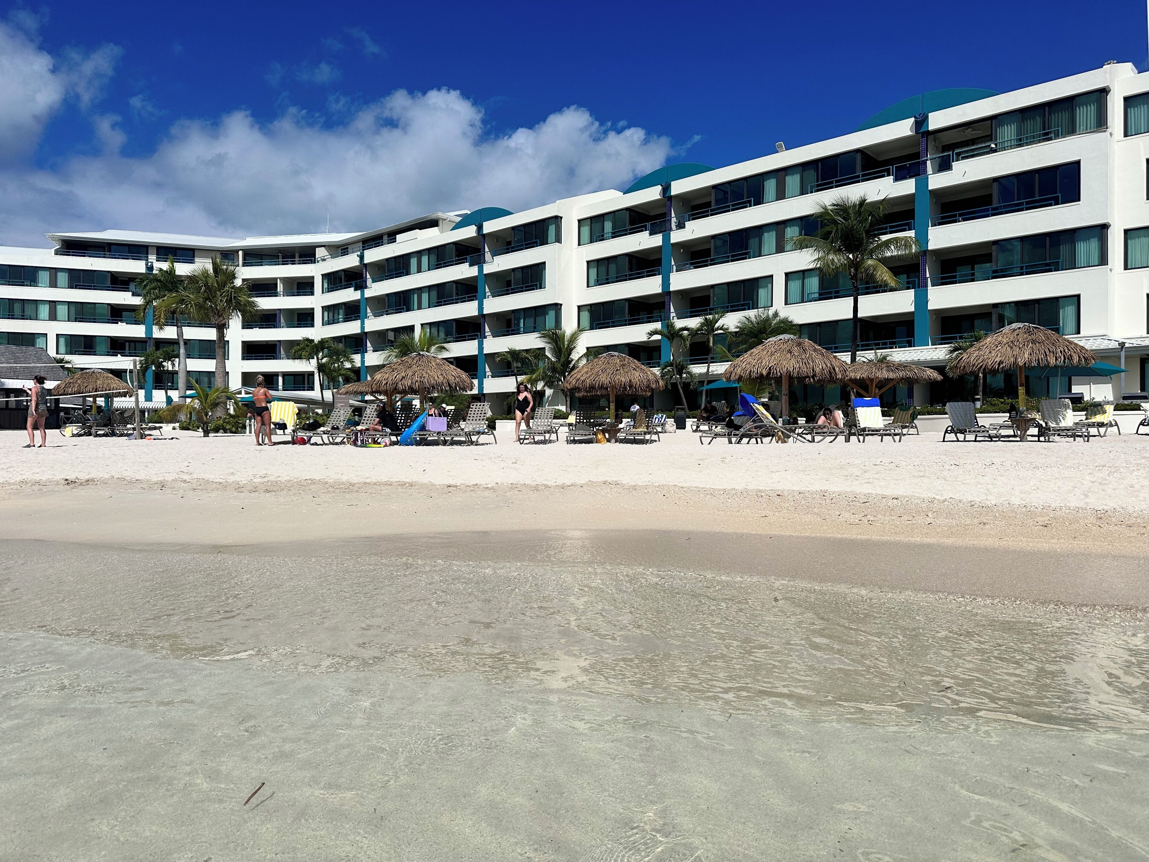 A beachfront hotel with multiple balconies, sun umbrellas, and a sandy beach.