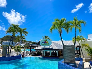 Una piscina cristallina circondata da palme e un bar sulla spiaggia.