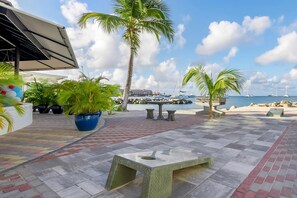 A patio area with a view of the sea, palm trees, and boats. - Amazing Sea Views Condo 3rd Floor with all amenities (Simpson Bay)